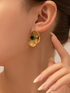 Detailed close-up of a vintage gold-plated stud earring with a green zircon on ear
