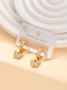 Detail of golden stainless steel butterfly earring with white zircon on stone background
