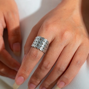 Close-up of wide silver open ring with intricate hollow floral patterns on finger