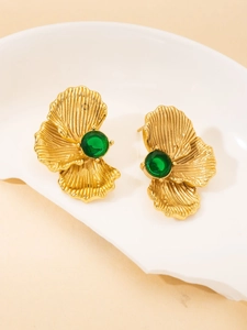 Detailed macro shot of vintage gold leaf earrings with round green gemstones in a white tray