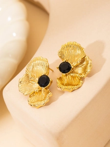 Macro detail of vintage gold-plated floral stud earrings with black zircon center
