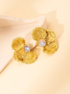 Macro detail of gold flower earrings with ribbed petals and central zircon stone