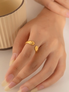 Dettaglio di un anello a forma di mani che abbracciano in oro indossato da una modella