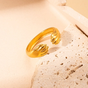 Dettaglio macro dell'anello dorato regolabile con design unico di mani che abbracciano