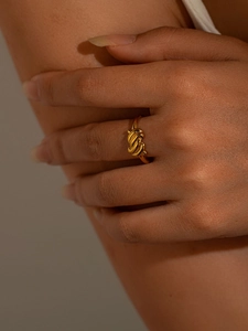 Vue détaillée d'une bague nœud en acier titane doré poli portée au doigt