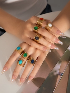 Primer plano de anillos dorados multicapa con piedras ovales de colores en la mano