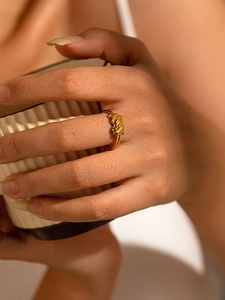 Gros plan d'une bague nœud torsadé en acier titane doré portée à l'index élégant