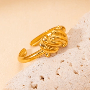 Gros plan détaillé d'une bague dorée ajustable au design torsadé sur un support en pierre