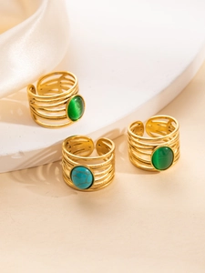 Primer plano de anillos multicapa dorados con piedras turquesas y gemas de ojo de gato