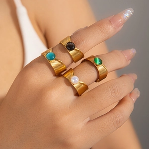 Detalle de cuatro anillos vintage dorados con piedras naturales redondas de colores