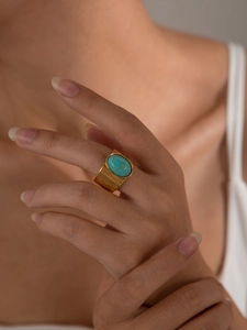 Goldener Titanring mit ovalem Türkisstein und gehämmerter Textur auf dem Finger getragen