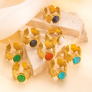 Anillos de hoja ajustables dorados con piedras preciosas en un soporte de piedra