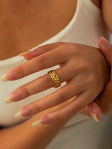 Gros plan d'une bague en titane doré gravée de motifs d'épis sur l'index