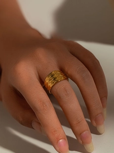 Gros plan d'une bague large en titane doré avec un motif texturé matelassé classique