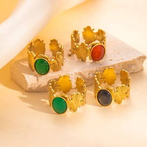 Anillos dorados ajustables con hojas y piedras ovaladas de colores en un soporte