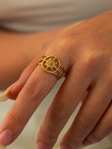 Détail d'une bague en titane doré avec relief circulaire et texture perlée sur modèle