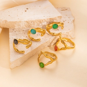 Set de anillos de acero de titanio diseño lava con gemas coloridas sobre base travertino