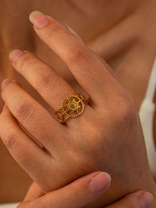 Détail macro d'une bague dorée en acier titane avec un motif radial de style bohème