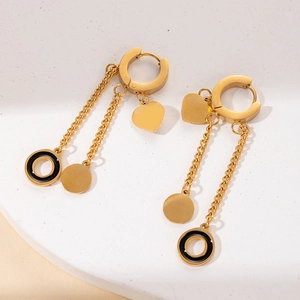 Detail of gold titanium heart tassel earrings featuring sleek black rings and chain drops