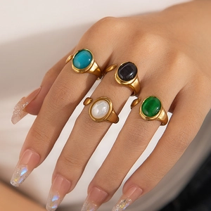 Primer plano de anillos de acero de titanio dorado con piedras preciosas de colores