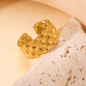 Détail macro d'une bague dorée en acier titane avec motif matelassé losange chic