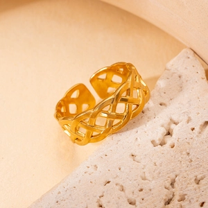 Détail d'une bague dorée ajourée à texture tressée sur un support en pierre naturelle