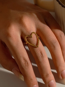 Détail d'une bague ouverte en forme de cœur doré avec texture martelée portée à l'index