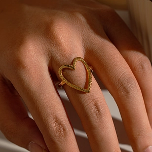 Gros plan détaillé d'une bague coeur dorée avec finition en métal martelé sur le doigt