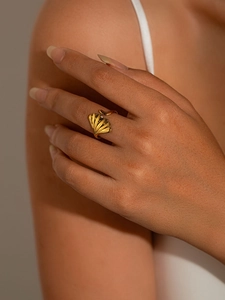 Gros plan détaillé de la bague feuille de ginkgo dorée montrant les textures sur le doigt