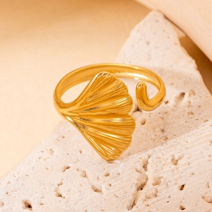 Vue détaillée d'une bague ginkgo dorée sur pierre montrant les textures du métal