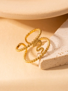 Detail eines vergoldeten Titanrings mit Perlenstruktur und Schlangenmotiv auf Travertin