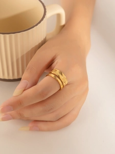 Detail of minimalist 18K gold plated titanium ring featuring wave textures on double layers