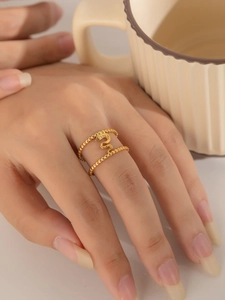 Detail eines zweilagigen goldenen Schlangenrings an der Hand mit edlem Perlendesign