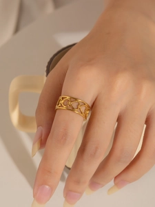 Primer plano de un anillo dorado con diseño de corazones calados puesto en el dedo