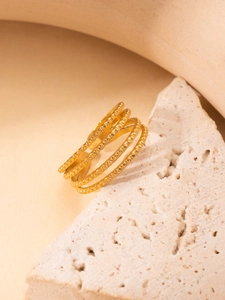 Macro shot of gold layered rings with fine textured beads on travertine stone base