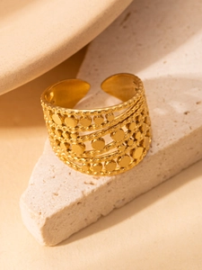 Nahaufnahme eines breiten, mehrlagigen goldenen Rings im Boho-Stil auf einem Steinsockel