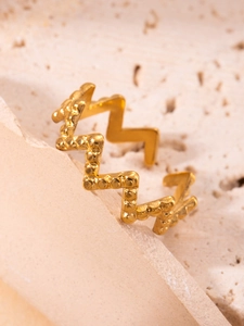 Detalle de anillo de acero de titanio dorado con diseño ondulado y textura granulada
