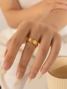 Detail of gold titanium ring featuring embossed star and moon patterns on a brushed surface