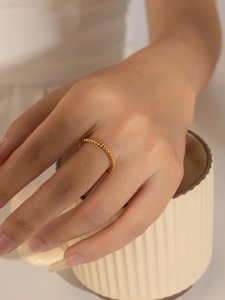 Primer plano de un anillo trenzado dorado en una mano que sostiene una taza de café