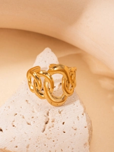 Detailed macro view of an adjustable gold-plated chunky link ring on a stone texture