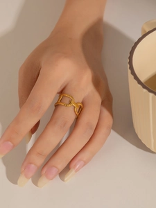 Primer plano de un anillo de cadena en forma de H dorado con textura trenzada