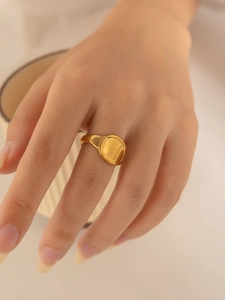Detailed macro view of a minimalist gold signet ring worn on a woman's middle finger