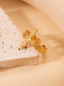 Detailed close-up of matte 18K gold-plated titanium cross ring on a textured white stone