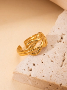 Detailed view of adjustable gold braided twist ring on a textured travertine stone