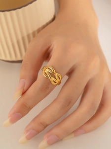 Close-up of minimalist gold twisted knot ring worn on index finger with elegant finish
