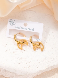 Détail de boucles d'oreilles créoles avec pendentif lune en acier doré sur pierre