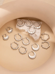 Detailed view of assorted geometric textured titanium steel hoop earrings on natural stone
