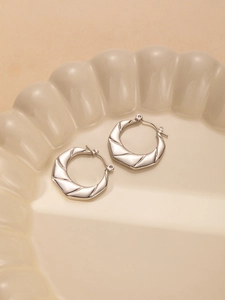Detail of silver twisted hoop earrings made of titanium steel with metallic texture