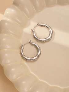 Macro detail of silver titanium steel hoop earrings with textured spiral design