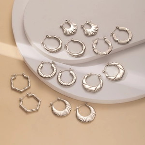 Collection of seven pairs of silver geometric titanium steel hoop earrings on white display